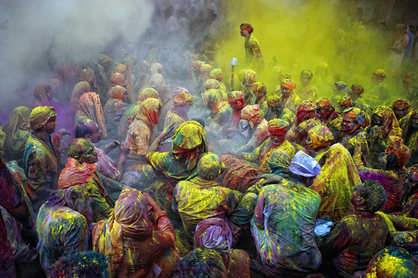 A man standing amidst the cloud of yellow color while the other people are singing bhajans of Radha and Lord Krishna. The festival of Holi is a religious festival and this day marks the beginning of Spring season in india. Taken during the celebration of Holi in India.by previous award winner, Poras Chaudhary.